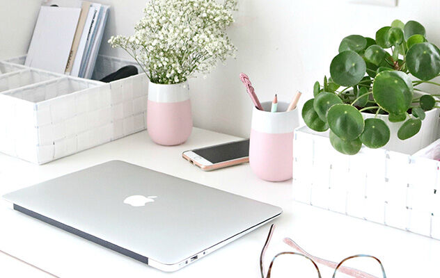 Ein Zahnputzbecher in rosa als Vase auf einem Schreibtisch