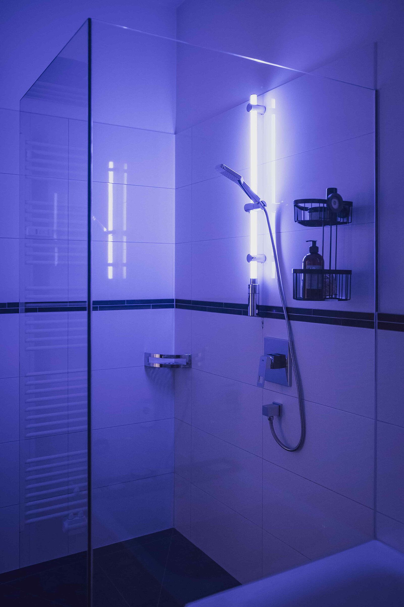 Eine elegante Glasdusche, welche durch die blau leuchtende LED Duschstange von WENKO ebenfalls blau erstrahlt