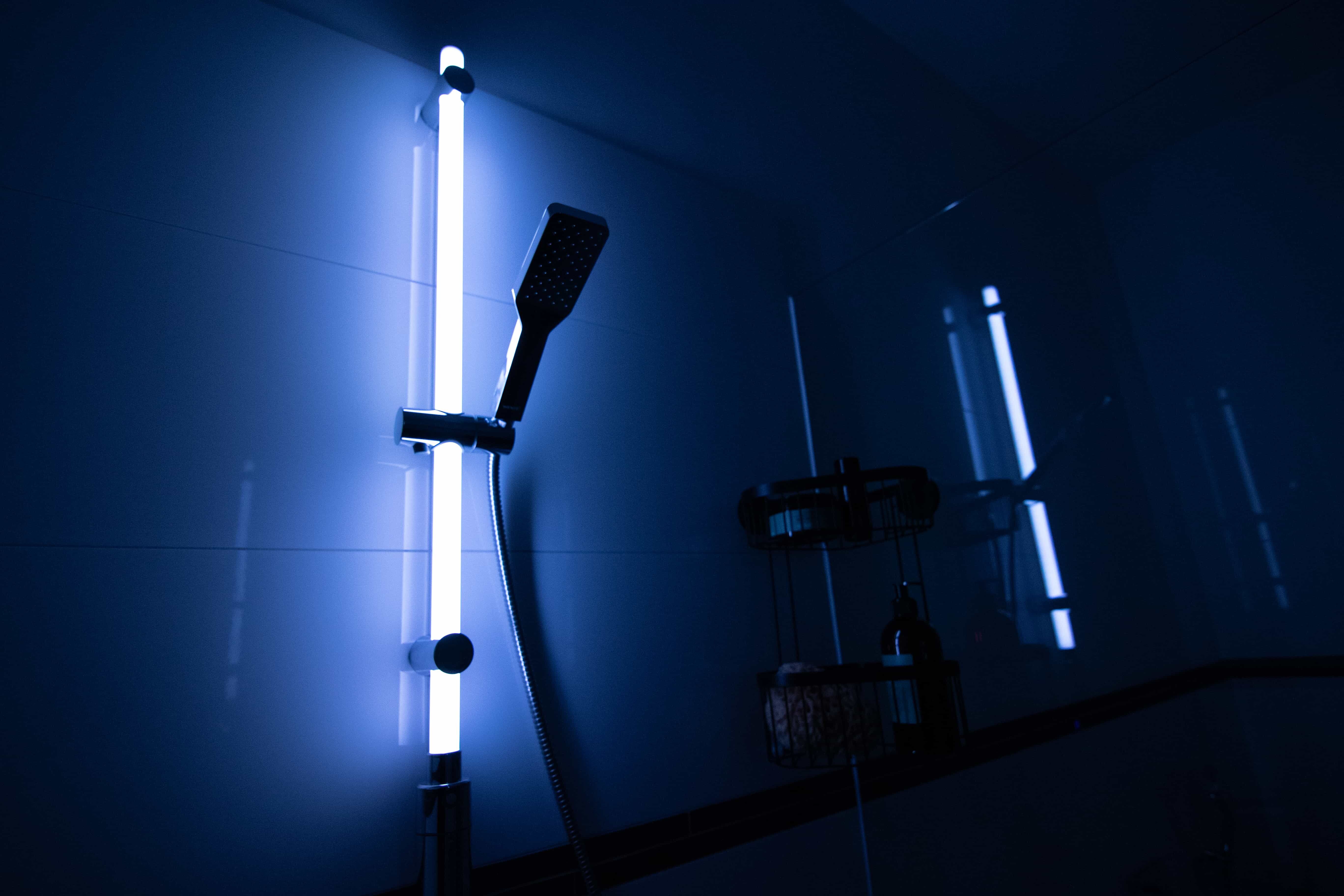 Eine leichtende Duschstange in einem dunklen Badezimmer